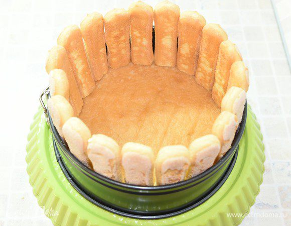 Переложить бисквит на блюдо, на котором будете подавать торт. Вокруг разместить разъемную форму. По периметру прямо на бисквит плотно друг к другу поставить печенье савоярди, слегка подрезав их снизу для устойчивости.