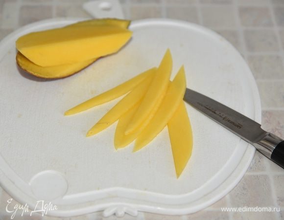 Перед подачей украсить торт по желанию. Я украсила розочками из свежего манго. Половину манго очистить от кожуры, нарезать половинки плодов на слайсы.  