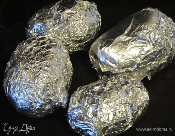 Картофель помыть, завернуть в пищевую фольгу, положить на противень и запекать в разогретой до 200 °С духовке 50 минут.