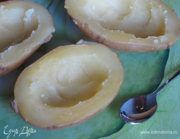 Картофель разрезать пополам и выложить на противень с фольгой. Аккуратно вынуть мякоть (удобнее всего это делать кофейной ложечкой) и слегка посолить.