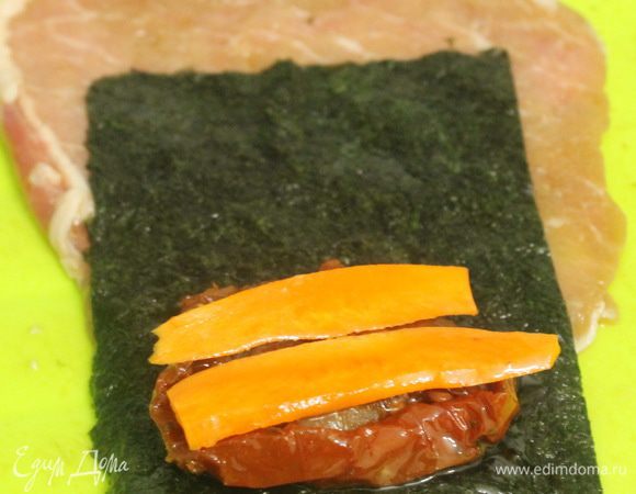 На кусок свиного филе положить лист нори, сверху кусочек моркови и вяленый помидор, и завернуть все в рулетик. Готовый рулетик завернуть в фольгу (в виде конфеты), сложить в сотейник, добавить овощной бульон или воду и тушить на небольшом огне минут 40. Готовые рулетики освободить от фольги и подавать к столу.