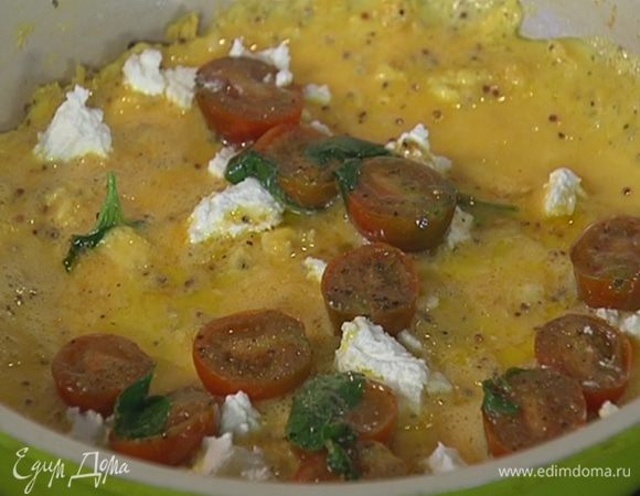 Козий сыр небольшими кусочками разложить на омлет, сверху выложить припущенные помидоры с базиликом.
