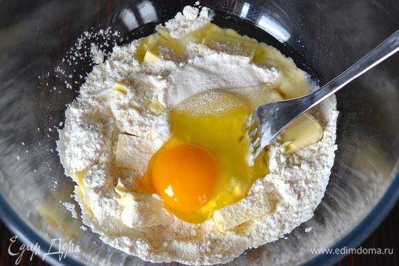 Первым делом для приготовления песочных сухариков в миске смешать просеянную муку, кусочки масла, соль и 1 яйцо.