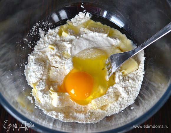 Первым делом для приготовления песочных сухариков в миске смешать просеянную муку, кусочки масла, соль и 1 яйцо.