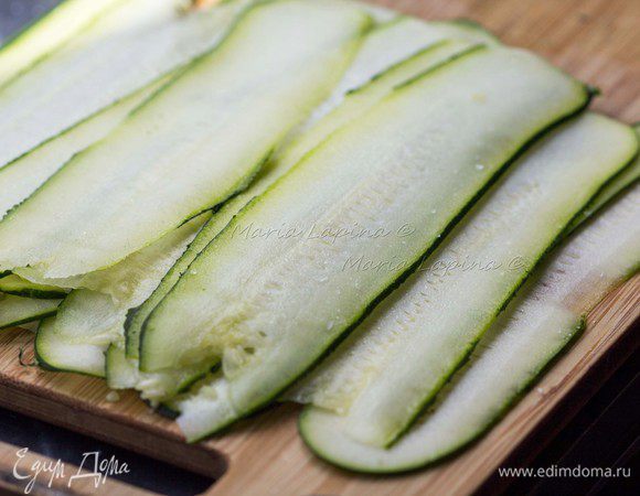 Цуккини нарезать тонкими пластами с помощью овощечистки. Присыпать их солью и оставить на 5 минут, они станут более эластичными и не будут ломаться при скручивании.