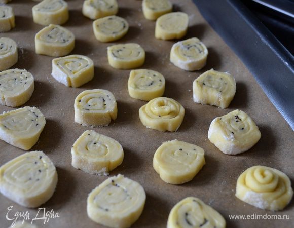 Духовку разогреть до 160°C. Противень застелить пекарской бумагой. Рулетики из теста нарезать на небольшие кружочки. Выложить на противень.