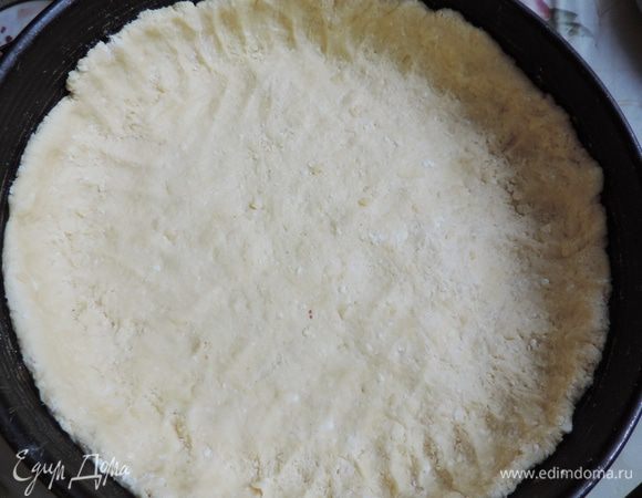 Охлажденное тесто руками распределяем по форме диаметром 26 см, выстеленной бумагой для выпечки. Бортики формы смазываем растительным маслом. Бортики из теста делаем почти на всю высоту формы.