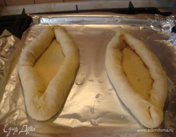 Раскатать в овал, по краям выложить фарш, завернуть и придать форму лодочки.