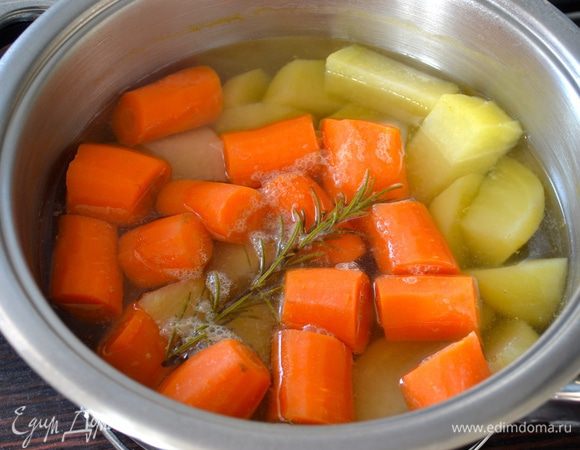 Очистить морковь и картофель. Одну морковку отложить в сторону. Остальные овощи нарезать кусочками, выложить в кастрюлю и залить холодной водой. Поставить на огонь, довести до кипения и варить 30 минут (я добавила веточку розмарина). 