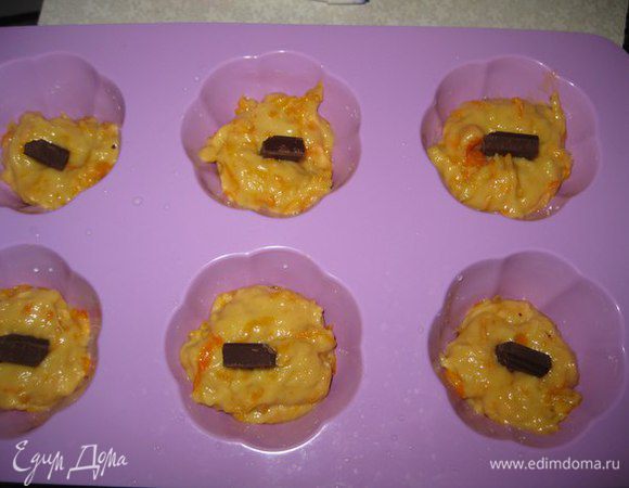 В формочки выложить по 1 чайной ложки теста, кусочек шоколада и наверх еще 1 чайную ложку теста.