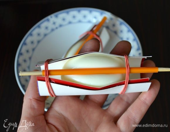 Сверху придавить по центру яйца подготовленной палочкой и зафиксировать ее с двух сторон резинками. У нас должна получиться вот такая "конструкция"... Дать яйцам остыть и затем нарезать их на ломтики острым ножом или специальным приспособлением для нарезки яиц.