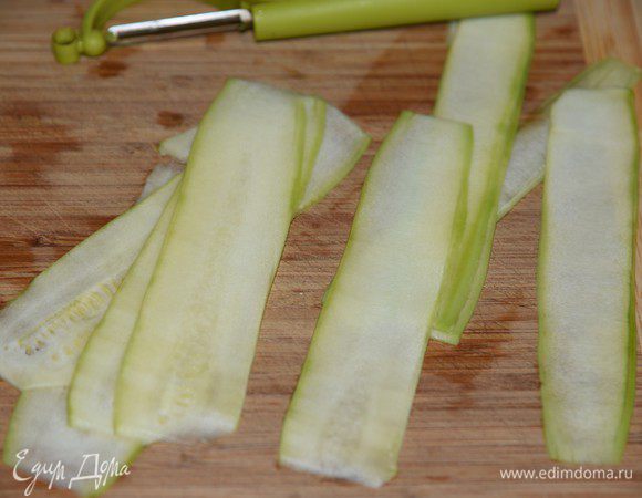 Спаржу разрезать на 2 части. 
Цукини помыть, почистить, нарезать овощечисткой на тонкие полоски.