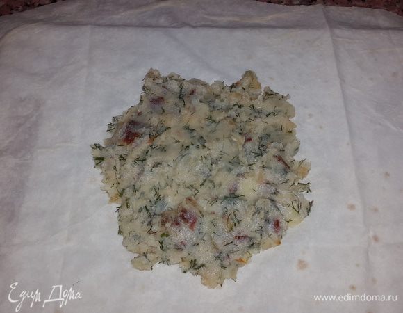 Лаваш разрезаем поперек на две части. Выкладываем в центр каждой части начинку, разравнивая ложкой, и формируем конветрик.