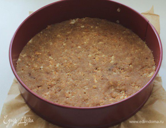 Разъемную форму  диаметром 24 см застелить бумагой для выпечки, и равномерно распределить песочную крошку. Утрамбовать и отправить в холодильник на 45-50 мин.