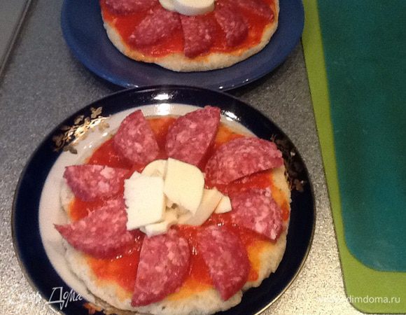 Смазываем основу томатным соусом, выкладываем колбаску в виде лепестков цветка, в серединку сыр, у меня домашний сулугуни. Духовку предварительно разогреем до максимума, ставим под гриль и через 5 минут пицца готова!
