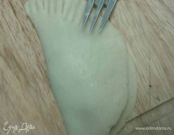 Свернуть полукругом и край прищепить вилкой. Внутренний край пирожка можно смазать водой, для того чтобы лучше скрепился.
