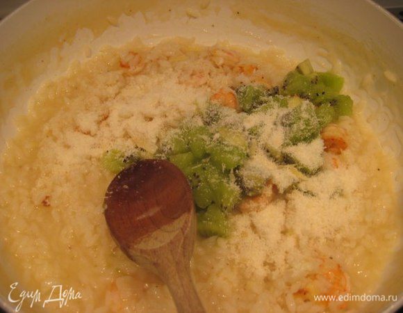 Готовое ризотто снять с огня, добавить киви, креветки, оставшееся сливочное масло и тертый пармезан. Попробовать на соль. Перемешать. Дать подружиться ароматам в течении 5 минут.