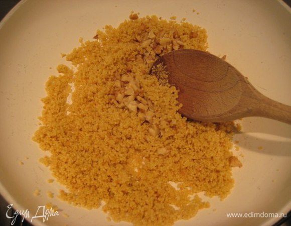 На оливковом масле обжарить 2 зубчика чеснока, чеснок выкинуть. Высыпать кус-кус и обжаривать, помешивая, 3 минуты. Добавить к кус-кусу измельченные грецкие орехи и оставшийся абрикосовый соус.