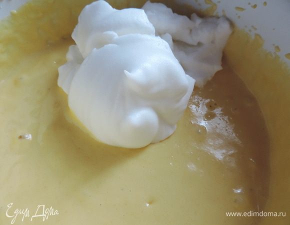 Добавляем растопленное горячее сливочное масло. Аккуратно перемешиваем лопаткой.
Теперь в три приема смешиваем тесто со взбитыми белками. Делаем это очень аккуратно, лопаткой, движениями снизу-вверх от краев к центру, чтоб не разрушить пузырьки воздуха. Ведь именно от них зависит воздушность бисквита, никаких других разрыхлителей в тесте нет.