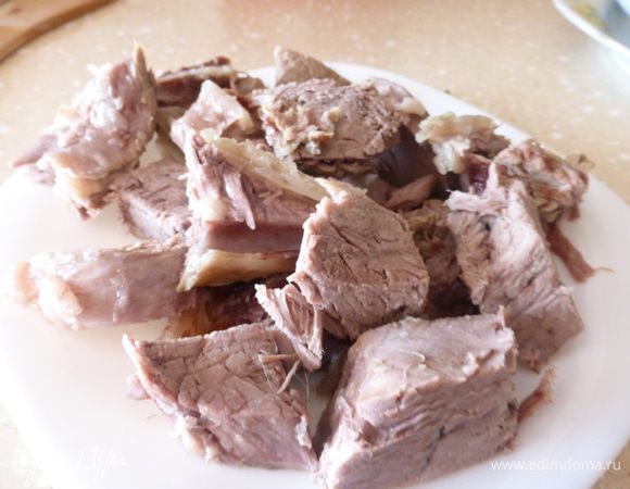 Готовое мясо извлечь из кастрюли, порезать на порционные кусочки и положить снова в бульон.