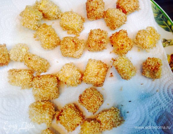 Масло нагреть во фритюрнице или в маленькой глубокой кастрюльке. Обжарить сырные кубики, до золотистого цвета кунжутной семени и положить на бумажную салфетку, чтобы избавиться от лишнего жира. 