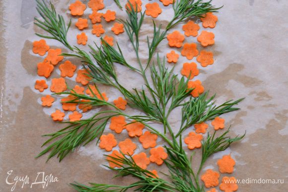С помощью овощечистки нарезать морковные полосы, плунжером сделать цветочки. Уложить на застеленный пекарской бумагой противень, формируя соцветия мимозы, чередовать веточками укропа.