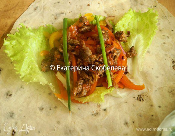 Лаваш развернуть, положить на него листья салата, затем часть маринованных овощей, сверху уложить говядину и зеленый лук. Завернуть лаваш, подогнув верхний и нижний края к начинке и свернув рулетом.