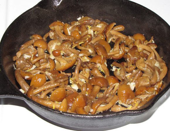 Грибы разморозить, отжать лишнюю влагу. Обжарить на растительном масле до готовности, добавить измельченный чеснок, цедру лимона, по вкусу посолить и приправить перцем, жарить еще 1-2 минуты. Остудить.