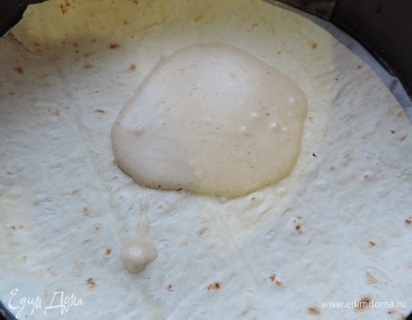 Я беру тонкий круглый лаваш. И немного обрезаю его по диаметру формы. Вы можете взять прямоугольный и подобрать форму соответствующего размера.
Приступаем к сборке пирога. На дно подходящей по диаметру, застеленной бумагой для выпечки формы кладем лист лаваша. Смазываем лаваш соусом (примерно 2 ст.л.).