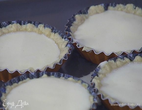 Охлажденные формы с тестом поместить в разогретую духовку на 5 минут, затем вынуть и залить подпеченное тесто кремом. Понизить температуру в духовке до 160°С и выпекать тарталетки с кремом 15–20 минут.