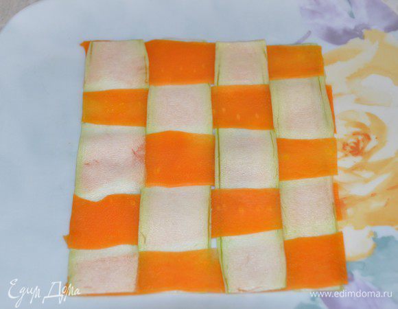 Сервируем наше блюдо. На большой тарелке выложить полосы кабачка и моркови и переплести их, как на фото. Выступающие края подрезать, чтобы получился квадрат.