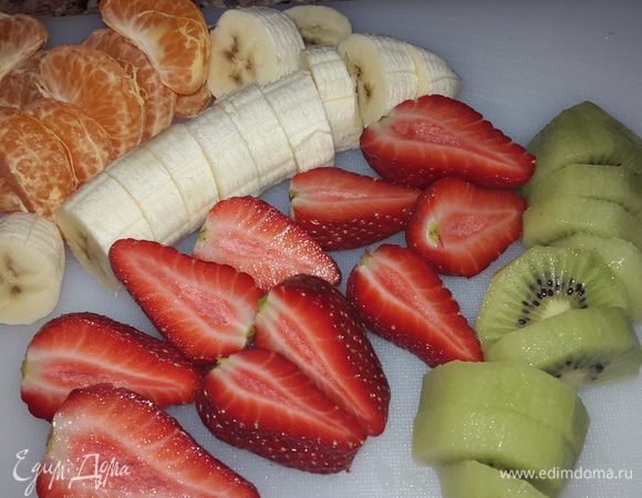 Мандарин чистим и разделяем на дольки, клубнику разрезаем вдоль пополам, банан очищаем и нарезаем кружочками толщиной примерно 1 см, киви чистим и нарезаем дольками.