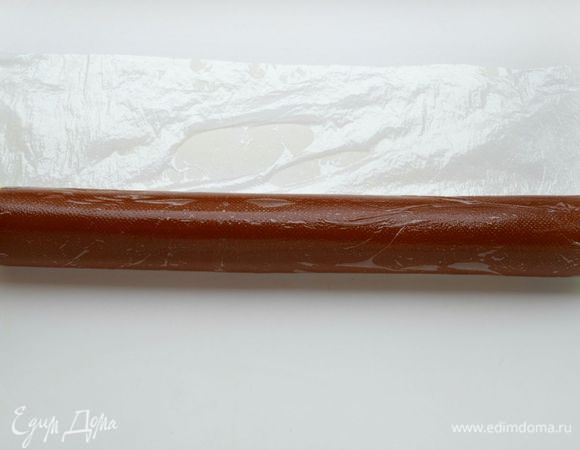 Чтобы рулет получился ровным и гладким, можно воспользоваться пищевой пленкой, завернуть в нее рулет и прокатать его руками на столе. Отправить на 3 минуты в морозильную камеру.