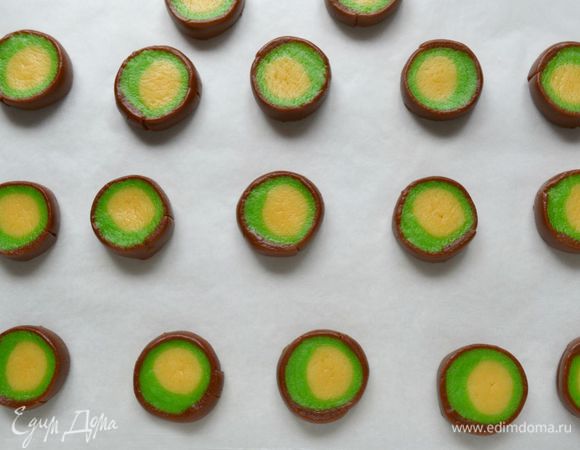 Острым тонким ножом нарезать рулет на колечки шириной примерно 3 см. Выложит на бумагу для выпечки. Руками подправить неровности и слегка приплюснуть.