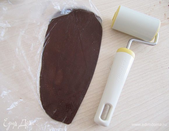 Делаем шоколадные розочки.
Растопить темный шоколад на водяной бане, добавить 2 ст. л. меда и мешать до загустения. Кладем в мешочек и оставить до затвердения. Я оставила на ночь, но можно было лепить сразу. Тесто у меня за ночь очень сильно затвердело, пришлось растапливать заново, оставила на пол часа, замесила руками тесто, получается как глина. Кладем в мешочек и раскатать тесто.
