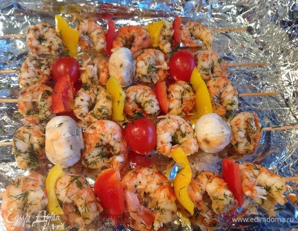 Почистите шампиньоны, болгарский перец нарежьте небольшими кусочками. Нанизывайте креветки на шпажки, чередуя их с овощами. Выложите на противень застеленный фольгой. Запекайте в духовке в режиме "Гриль", при температуре 200 градусов, около 20 минут.