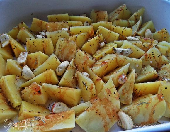 Сливаем картошку, распределяем в один слой в керамической форме, сверху разбрасываем чеснок и поливаем заправкой.