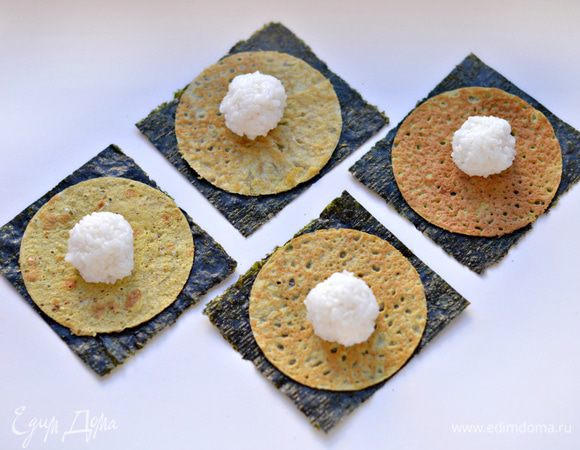 На каждый квадрат нори положить яичный блинчик (он по размеру должен быть меньше, чем квадрат нори).
Из риса скатать небольшой шарик, смочив руки водой. 
Уложить на яичный блинчик.