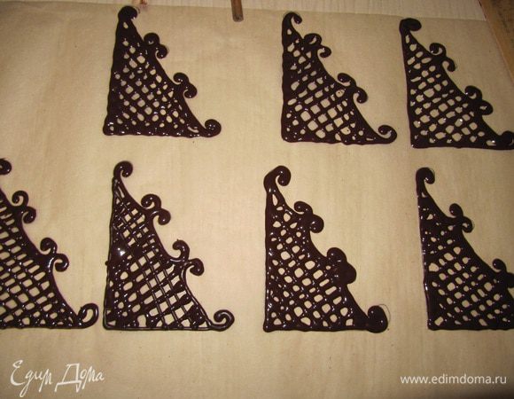 Украшение треугольники. Часть горячего шоколада положите на лист бумаги, разровняйте лопаткой и дайте остыть вырежьте круг диаметром 12 см. Нарисуйте рисунок на пекарской бумаги, 7 см основание, высота 10 см, в середине нарисуйте решетку. Обведите шоколадом контуры рисунка, дайте остыть. На диск из шоколада налейте несколько капель растопленного шоколада, установите затвердевшие треугольники, соединив их в центре.