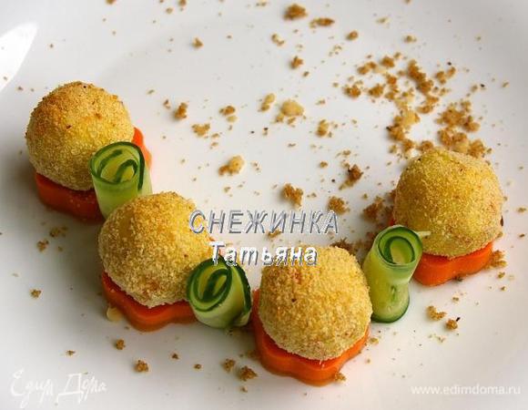 Блюдо для подачи посыпаем крошкой из хлеба и фундука. Выкладываем сливочно-морковную «подушку». На неё «колобки». Между «цветочками» ставим рулетики из огурца.