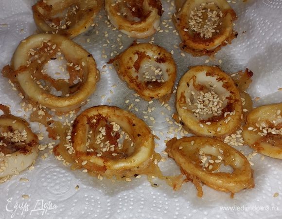 Готовые кальмары выкладываем на бумажное полотенце, чтобы убрать излишки масла и посыпаем кунжутом.