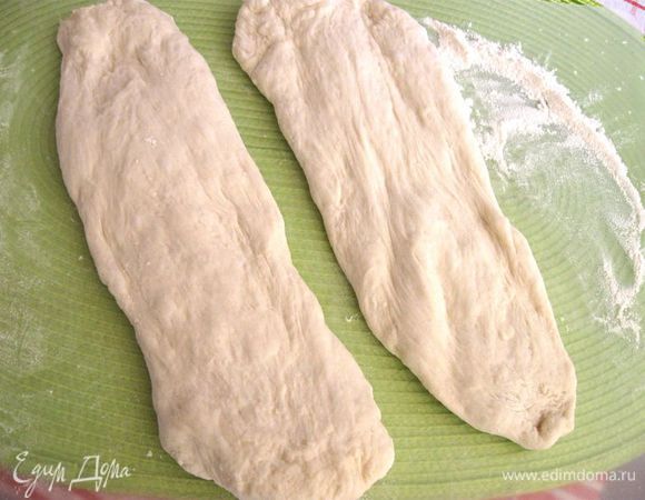 Духовку разогреть до 250С. Поставить в нее нижний поддон, в который потом (когда будете отправлять хлеб на выпечку) нальете горячую воду.  Выложить тесто на стол, разделить пополам, немного расправить руками. Я пекла из половины от приведенной порции. 