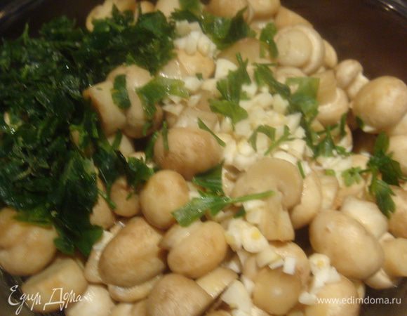 Грибы выложить в глубокую тарелку или кастрюльку, в которой мы их будем заправлять. В горячие грибы добавить порезанный чеснок, зелень.