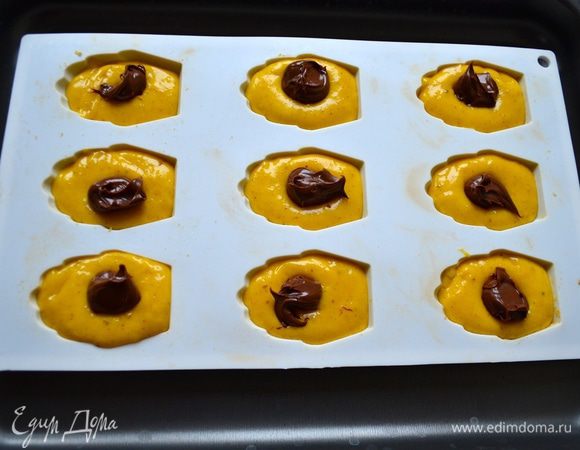 В формочки для мадлен положить столовую ложку теста. Сверху - чайную ложку шоколадной пасты.