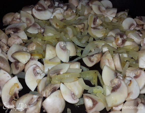 Репчатый лук режем на четверть кольца и обжариваем на оливковом масле. Когда лук поджарится и станет мягким добавляем к нему нарезанные ломтиками шампиньоны, перемешиваем, тушим до упаривания жидкости.