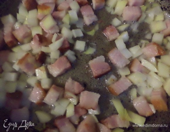 Бекон нарезать кубиками и обжарить на сухой сковороде до появления румяной корочки. Добавить рубленый лук и обжарить его до полупрозрачности.
