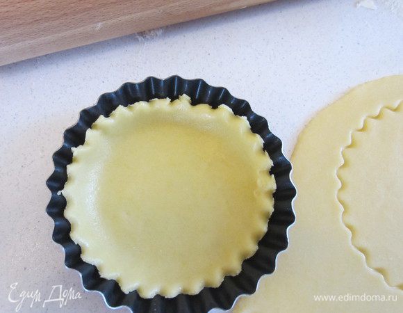 Тем временем раскатываем тесто, вырезаем кружочки, раскладываем тесто по формочкам.