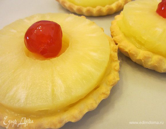 Сверху кладём кружки ананаса и засахаренную вишню.