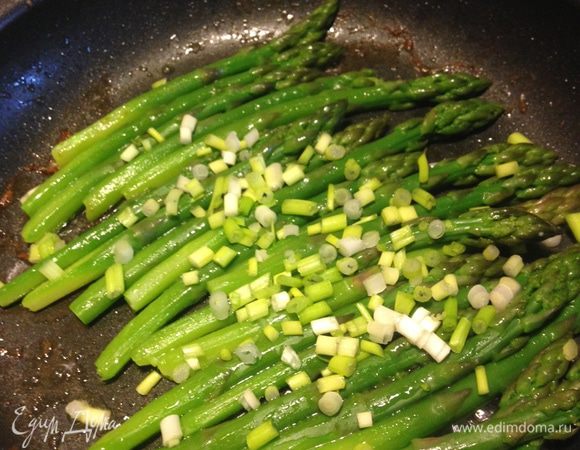 Выложить в сковороду спаржу с зелёным луком и слегка подрумянить.