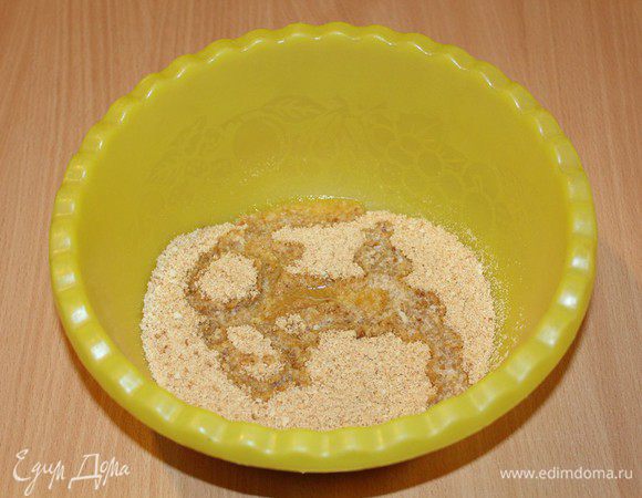 Печенье измельчите в мелкую крошку, перемешайте в миске с растопленным маслом.